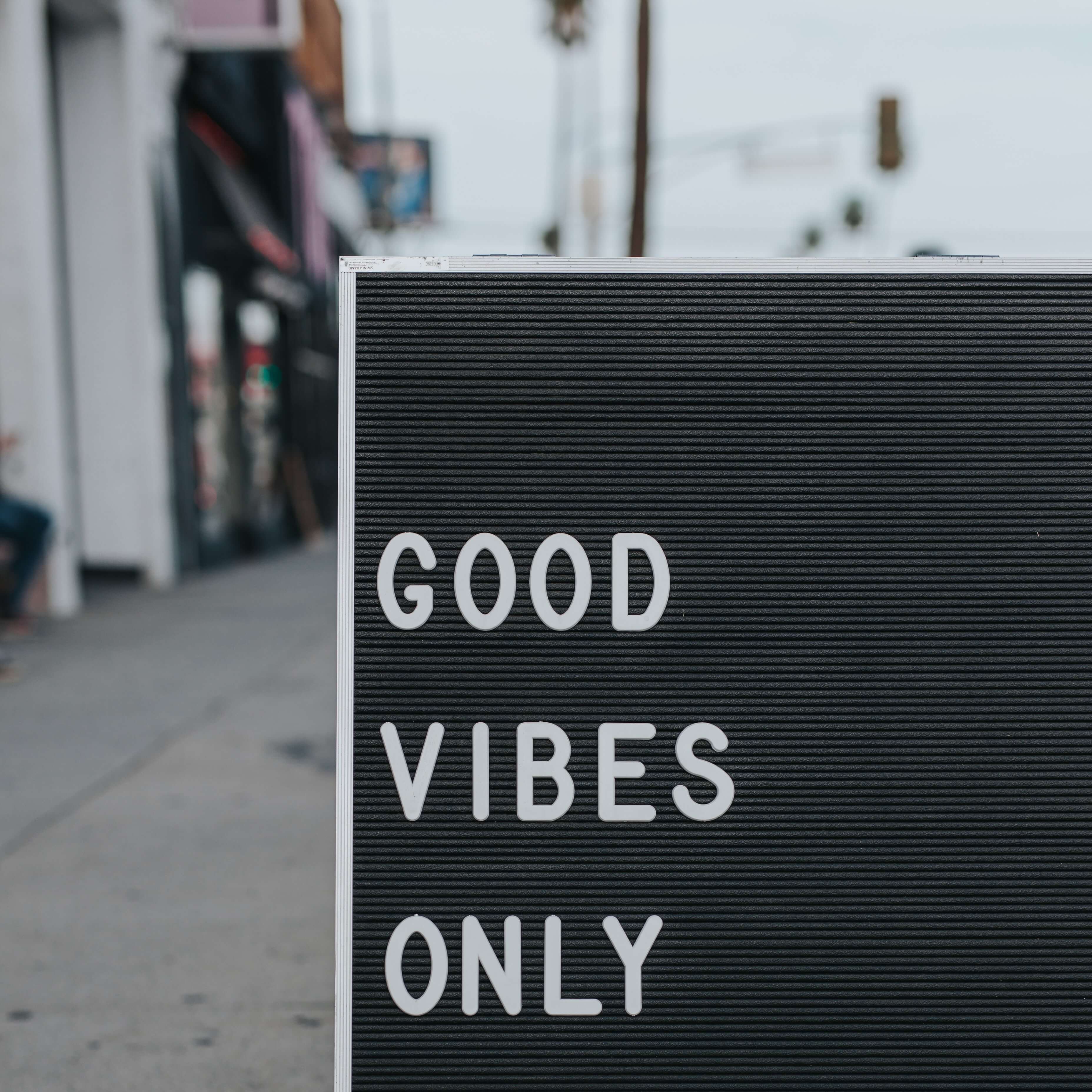 sandwich board on pavement with words good vibes only