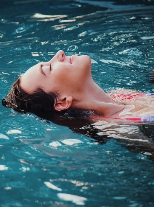 women eyes closed floating in pool