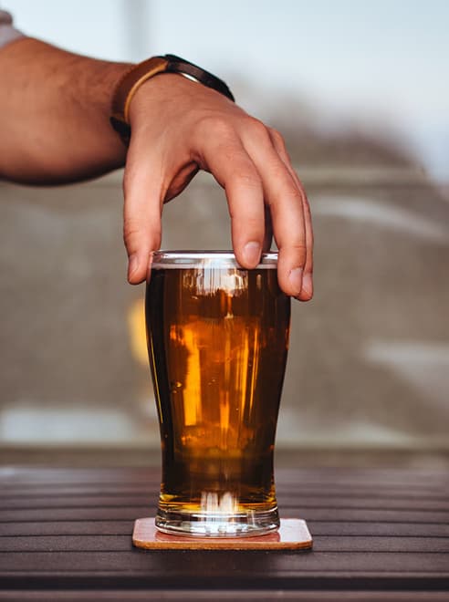man holding pint of beer at the top of the glass
