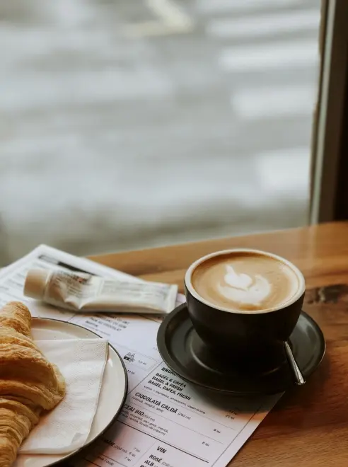 coffee and a croissant sat on a table in front of a window