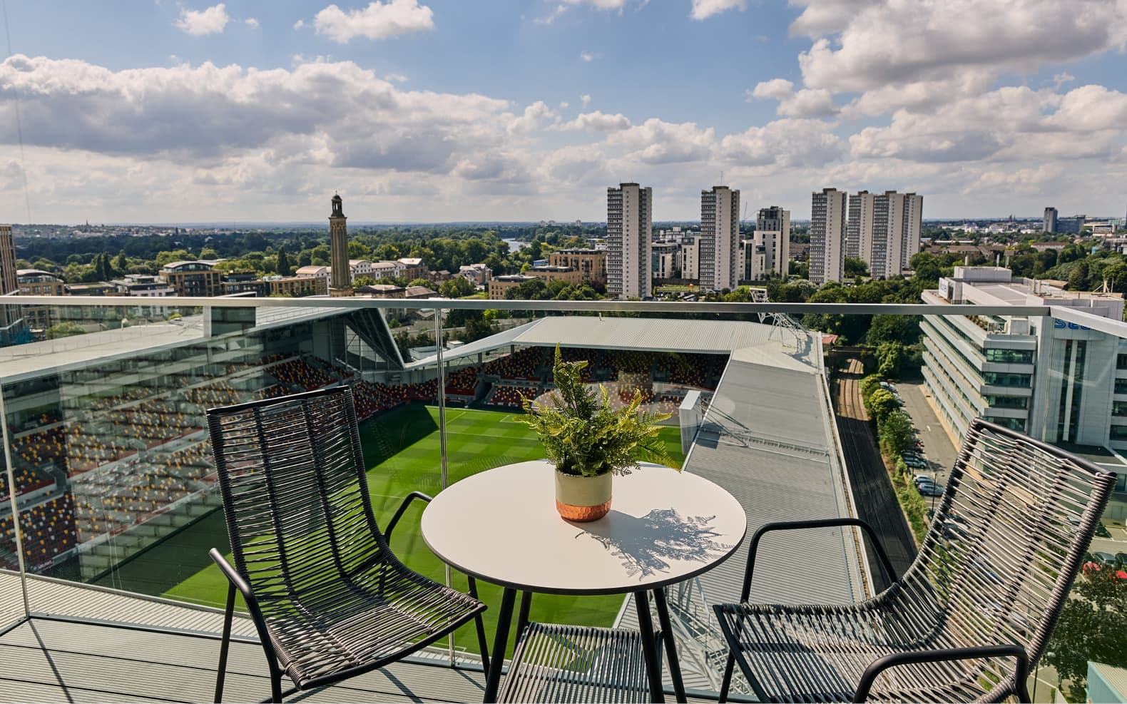 balcony with bistro table and chairs overlooking Brentford football ground