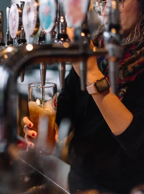 several beer taps and person behind seen pouring a pint
