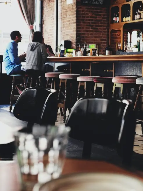 two people sitting at the bar, pub chairs in the foreground